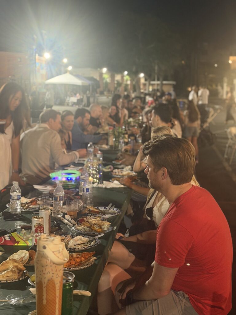 Families eating dinner at long tables under the lights