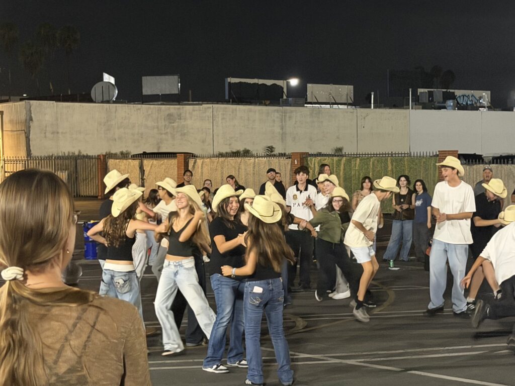Dancers in cowboy hats moving together at night
