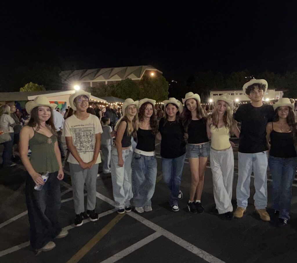 A row of high school volunteers in cowboy hats at night