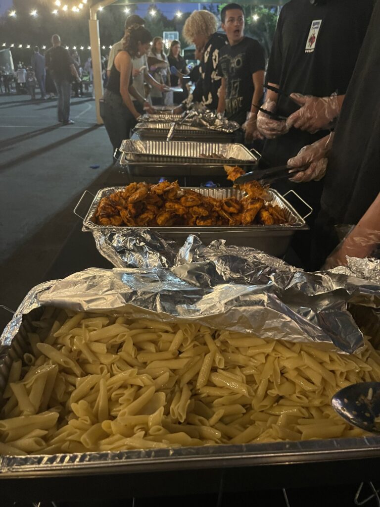 Volunteers serving pasta and chicken from the buffet line
